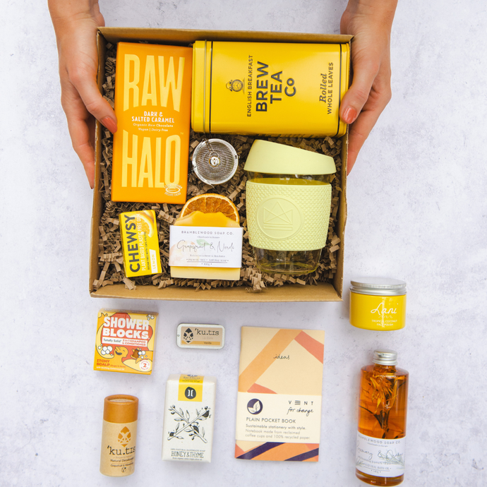 Selection of yellow and orange corporate gifts in a recycled cardboard box